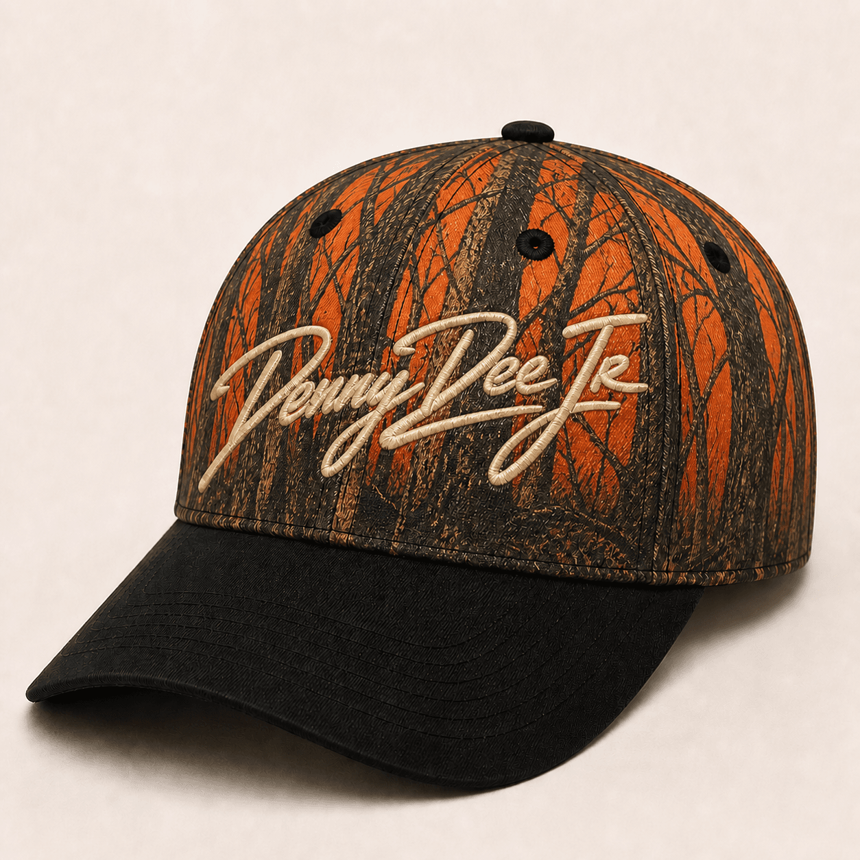 Blaze-orange bottomland-inspired bark camo baseball cap with a black brim and warm-bone embroidered Denny Dee Jr signature